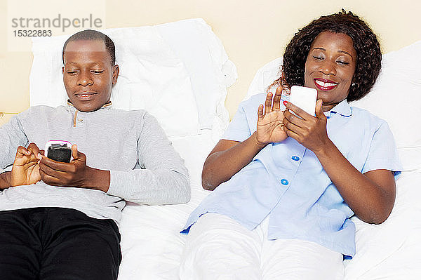 Dieses junge Paar ist glücklich  wenn es sein Handy im Bett benutzen kann.
