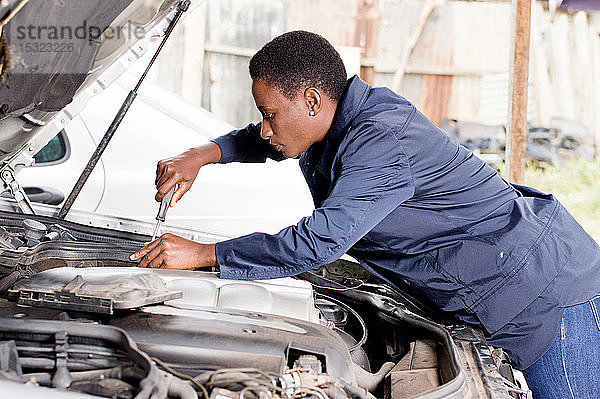 Eine Mechanikerin repariert den Motor eines Autos in ihrer Werkstatt.
