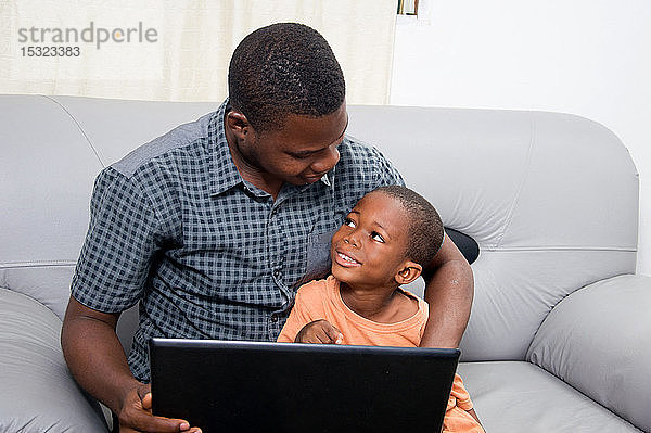 Der Vater freut sich  dass sein Kind einen Laptop kennenlernt und mit ihm arbeitet.