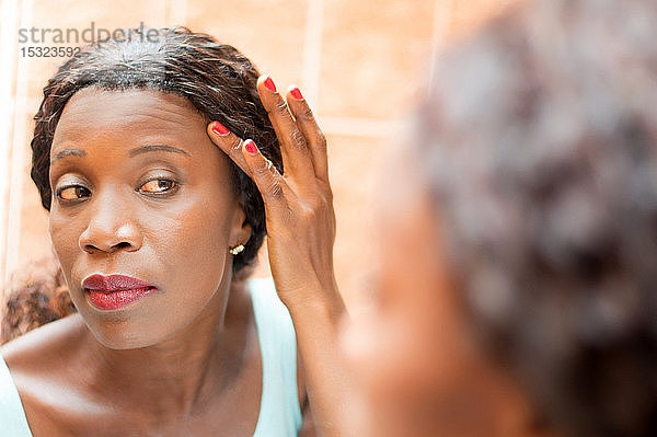 Die junge Frau schaut in den Spiegel  um sich richtig zu schminken.