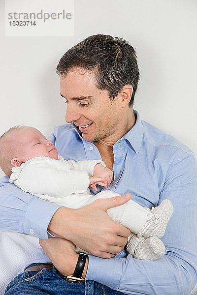 Junger zärtlicher Vater  der sein 2 Monate altes Baby im Arm hält.