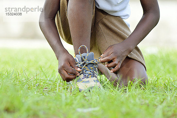 Ein Kind Knie  binden seine Schuhe Lanzen  besser zu laufen.