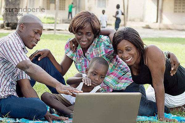 Eine Gruppe von Freunden und ein Kind schauen auf einen Laptop-Bildschirm. Sie sind alle glücklich.