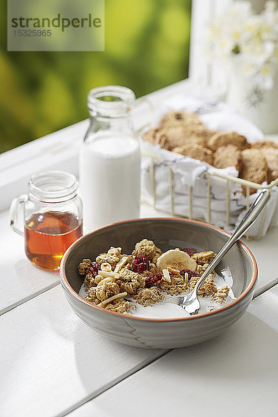 Granola Breakfast Bowl mit Schokoladenkeksen und frischer Milch am Fenster