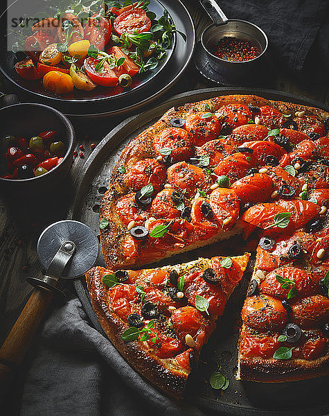 Eine Tomatenpizza mit Oliven und Pinienkernen