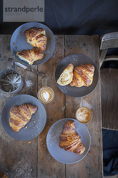 Croissants mit Cappuccino auf einem rustikalen Holztisch (Ansicht von oben)