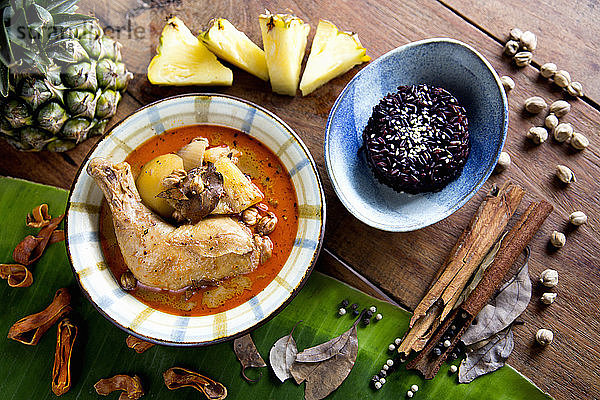Thailändisches Hühner-Massaman-Curry  serviert auf flauschigem  schwarzem Jasminreis