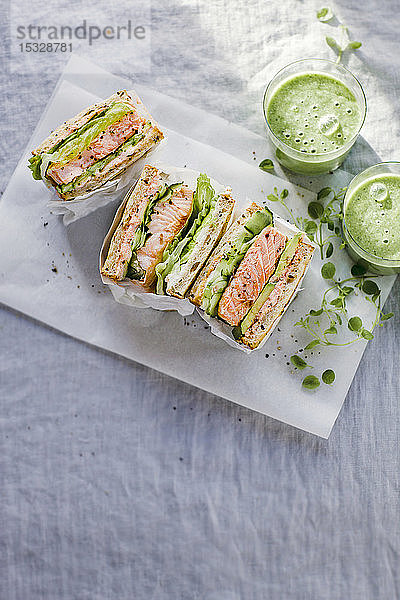 Toast-Sandwich mit Lachs  Gurke  Avocado  Kaviar und Frischkäse  serviert mit grünem Smoothie