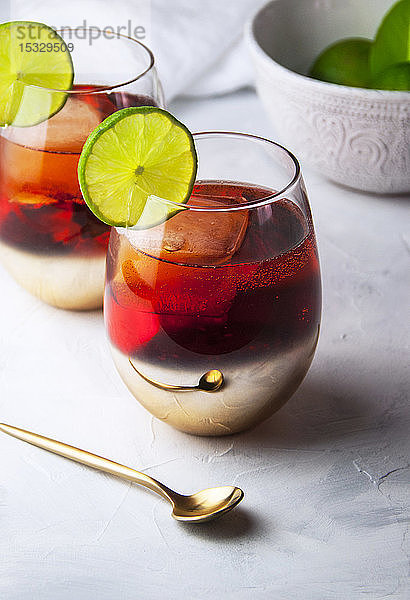 Zwei Gläser Aperol Spritz-Cocktail mit Limettenbeilage