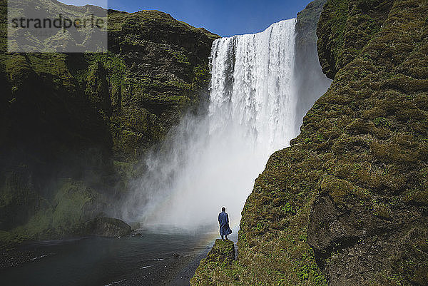 Mann vor dem Wasserfall Skogafoss in Island