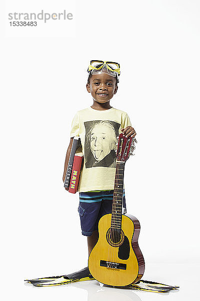 Junge mit Einstein-T-Shirt und Tauchermaske hält Gitarre und Bücher