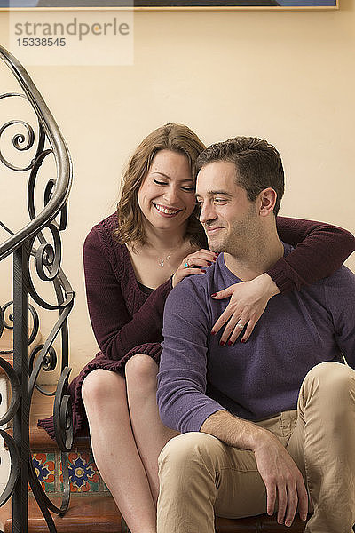 Lächelndes junges Paar auf einer Treppe sitzend