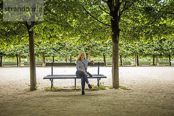 Frau auf Parkbank unter Bäumen in den Palais-Royal-Gärten in Paris  Frankreich
