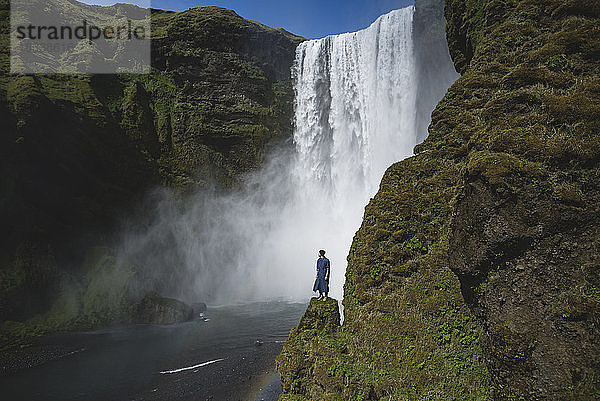 Mann vor dem Wasserfall Skogafoss in Island