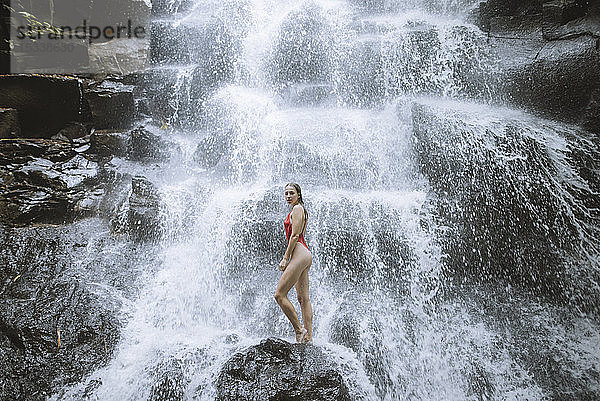 Frau im roten Badeanzug am Wasserfall auf Bali  Indonesien