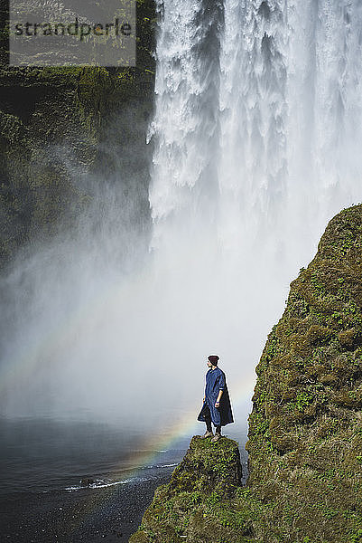 Mann vor dem Wasserfall Skogafoss in Island