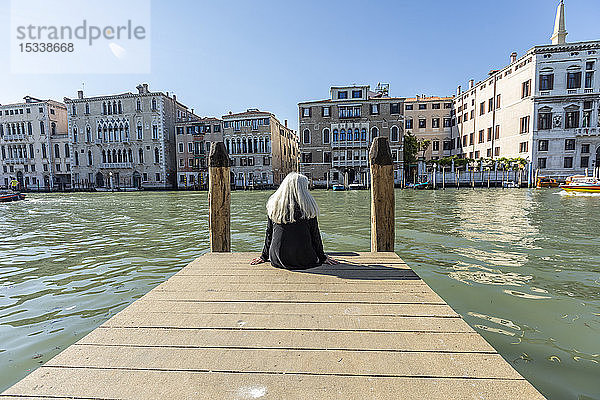 Frau sitzt auf einem Steg am Canal Grande in Venedig  Italien