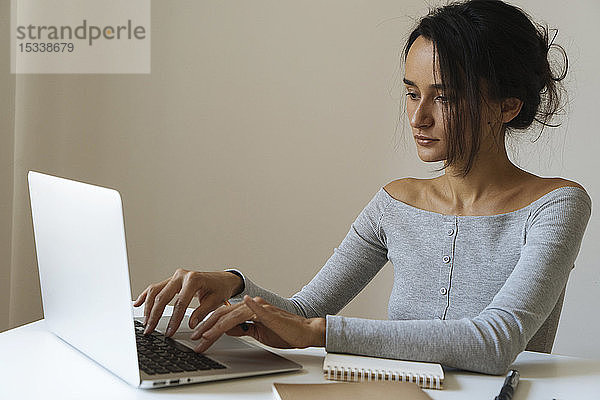 Frau mit Laptop und Notizblöcken