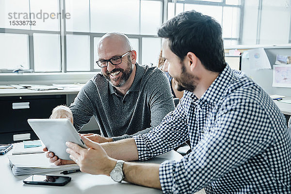 Männer benutzen ein digitales Tablet während einer Besprechung im Büro