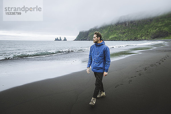 Mann spaziert am Strand in Vik  Island