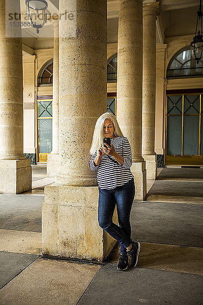 Frau mit Smartphone vor den Säulen des Palais-Royal in Paris  Frankreich