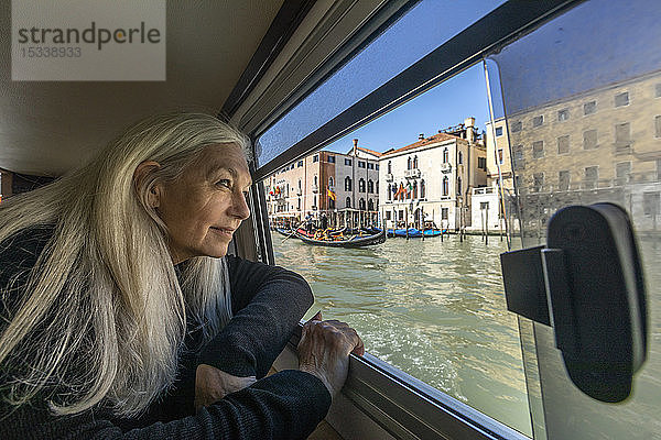 Frau schaut aus einem Bootsfenster auf dem Canal Grande  Venedig  Italien