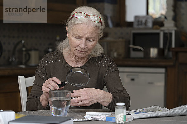 Ältere Frau liest das Etikett einer Pillenschachtel