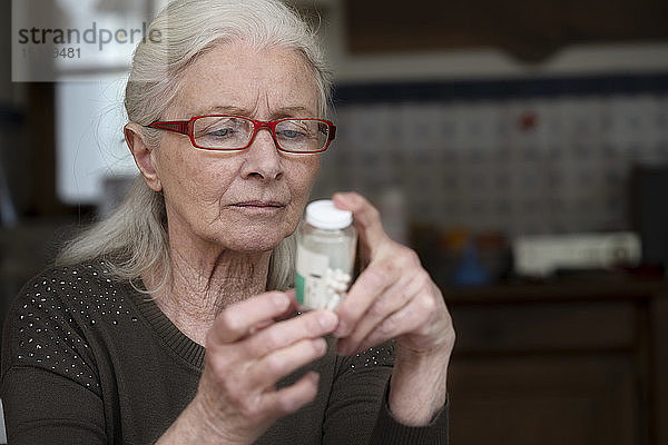 Frau liest Etikett einer Pillenflasche