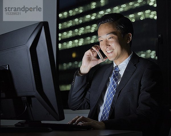 Junger japanischer Geschäftsmann arbeitet spät in der Nacht
