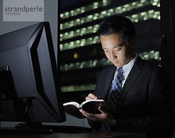 Junger japanischer Geschäftsmann arbeitet spät in der Nacht