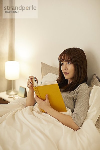 Junge japanische Frau im Bett