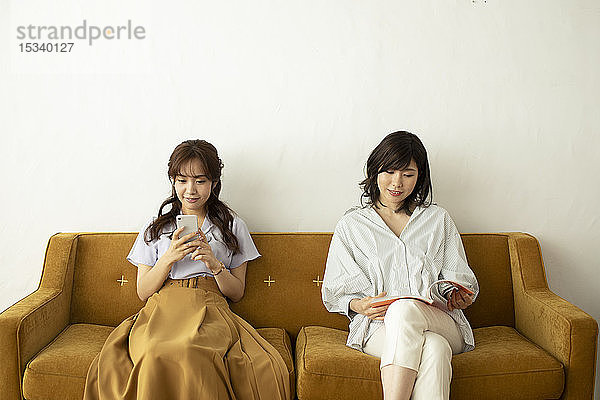 Junge japanische Frauen auf dem Sofa
