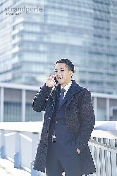 Junger japanischer Geschäftsmann im Freien