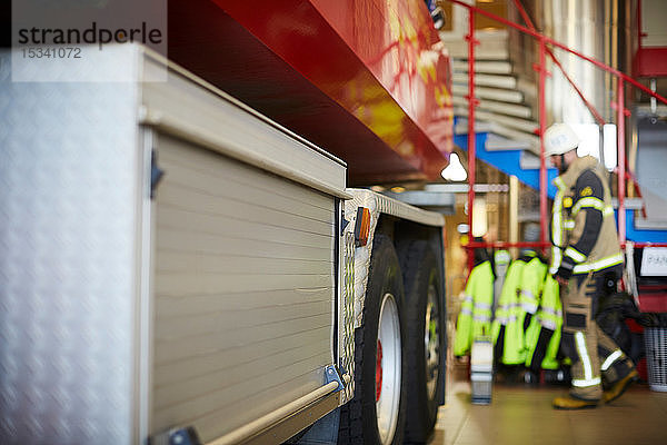 Beschnittenes Bild eines Feuerwehrwagens mit Arbeiter im Hintergrund in der Feuerwache