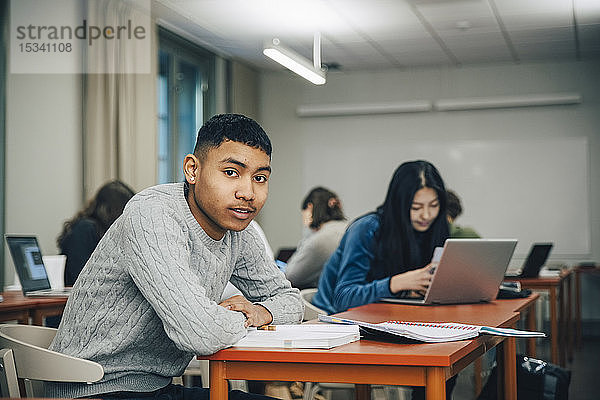 Porträt eines Teenagers  der im Klassenzimmer am Schreibtisch sitzt