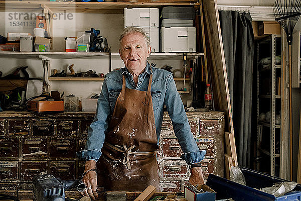 Porträt eines selbstbewusst lächelnden älteren männlichen Eigentümers beim Workshop stehend
