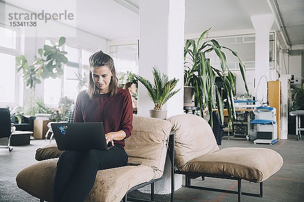 Selbstbewusste kreative Geschäftsfrau mit Laptop im Büro