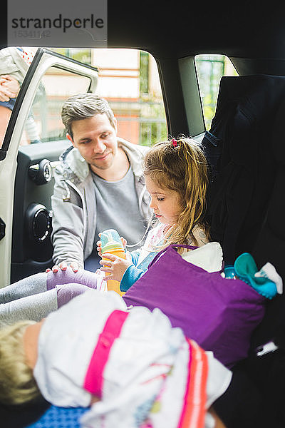 Vater spricht mit traurigem Mädchen  das im Auto sitzt