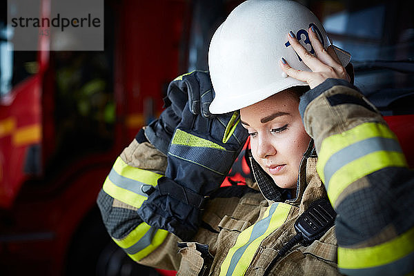 Weibliche Feuerwehrfrau mit Helm beim Blick auf die Feuerwache