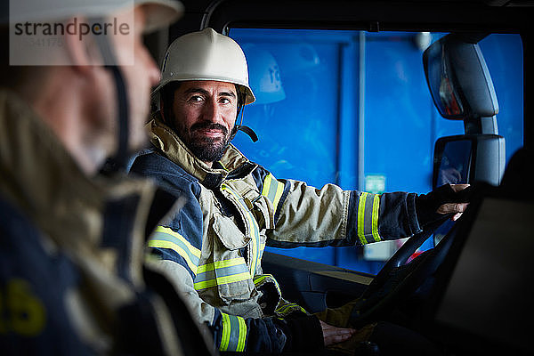 Feuerwehrmann sieht seinen Kollegen an  während er im Feuerwehrauto sitzt