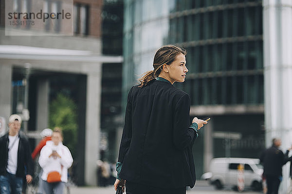 Rückansicht einer Geschäftsfrau  die beim Gehen auf der Straße in der Stadt wegschaut