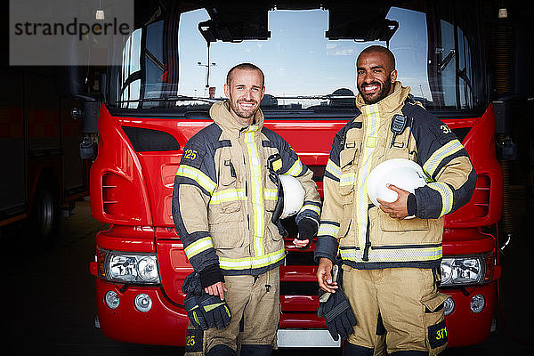 Porträt von Mitarbeitern  die in der Feuerwache vor dem Feuerwehrauto stehen