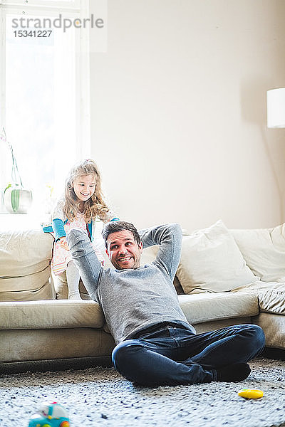 Fröhlicher Vater und Tochter spielen zu Hause im Wohnzimmer