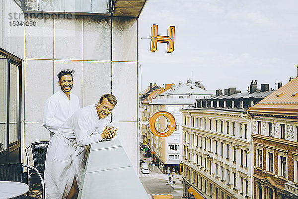 Lächelndes schwules Paar genießt Hotelbalkon