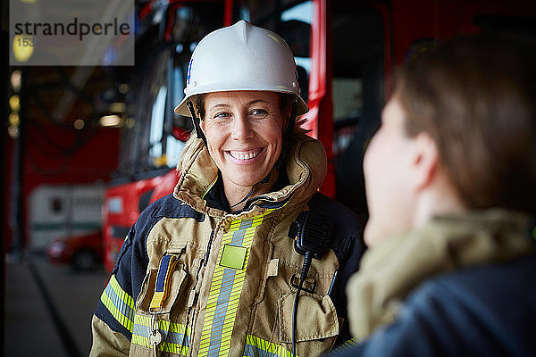 Lächelnde Feuerwehrfrau sieht Mitarbeiterin in Feuerwache an