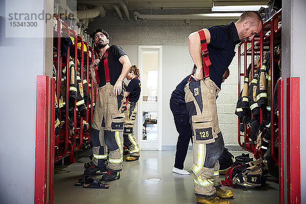 Feuerwehrleute tragen Arbeitsschutzkleidung in der Umkleidekabine der Feuerwache