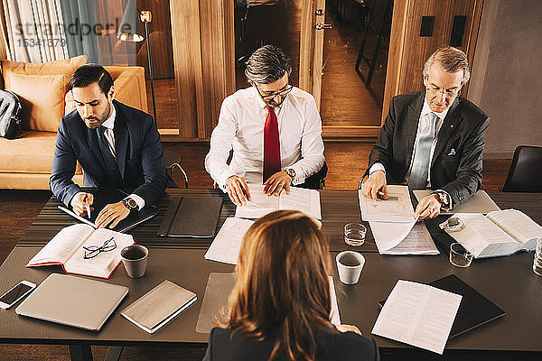 Hoher Blickwinkel auf weiblichen Finanzberater bei der Planung mit männlichen Anwälten bei einem Treffen im Sitzungssaal
