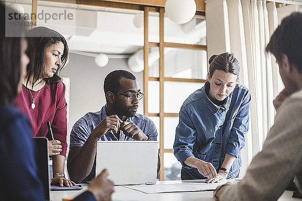 Geschäftsfrau erklärt den Kollegen am Tisch bei einer Sitzung im Sitzungssaal die Strategie