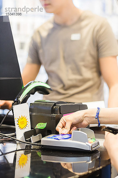 Hände einer Kundin  die an der Kasse mit Kreditkarte bezahlt