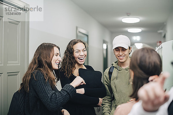 Fröhliche jugendliche Studenten stehen im Korridor